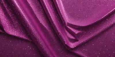 The primary subject of the image is a purple curtain with glittery sequins on it. The setting is a room with a purple backdrop. The visual style is a close-up of the curtain, showcasing its sequin pattern. The colors and mood of the image are predominantly purple, with the sequins adding a touch of glitter and sparkle.