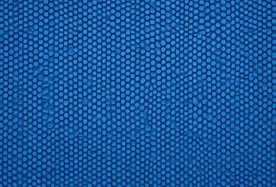 The primary subject of the image is a blue surface with a pattern of white dots. The setting appears to be a blue background, and the visual style is a close-up of the blue surface with the white dots. The colors and mood of the image are predominantly blue and white, creating a calm and serene atmosphere.