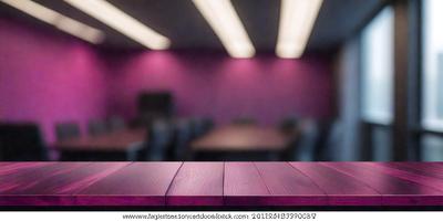 The primary subject of the image is a wooden table with a purple tablecloth. The table is surrounded by several chairs, creating a cozy and inviting atmosphere. The setting appears to be a dining area or a meeting room, with a focus on the table and chairs. The visual style of the image is a photo, capturing the details and textures of the wooden table and chairs. The colors and mood of the image are predominantly purple, giving it a warm and inviting feel.