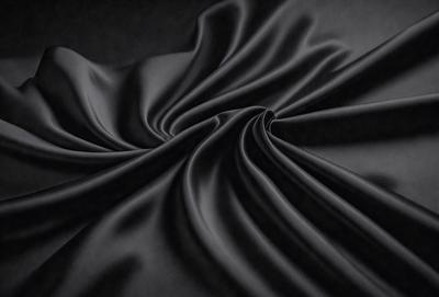 The primary subject of the image is a black fabric, which appears to be a piece of cloth or a curtain. The setting is a dark room, and the visual style is a close-up of the fabric. The colors and mood of the image are predominantly dark and moody, with the black fabric as the main focus.
