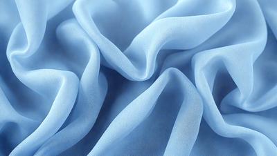 The primary subject of the image is a blue fabric, which appears to be a piece of cloth or a sheet. The setting is a close-up of the fabric, showcasing its texture and details. The visual style is a realistic representation of the fabric, and the colors are predominantly blue, giving the image a calm and soothing atmosphere.