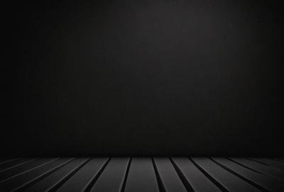 The primary subject of the image is a black wall. The setting is a dark room, and the visual style is a black and white photo. The colors and mood of the image are predominantly dark and moody, with the black wall serving as the focal point.
