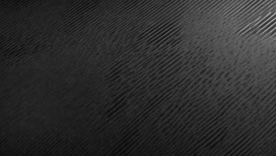 The primary subject of the image is a close-up of a black and white pattern, which appears to be a textured surface. The setting is a black background, and the visual style is a pattern or texture. The dominant colors are black and white, and the overall atmosphere is somewhat mysterious or intriguing.