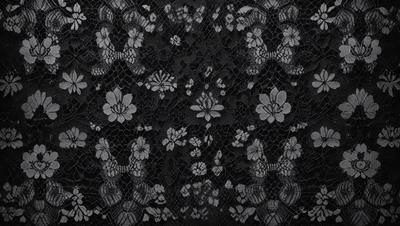 The primary subject of the image is a black lace pattern with white flowers. The setting is a black background, and the visual style is a close-up of the lace pattern. The dominant colors are black and white, creating a classic and elegant atmosphere.