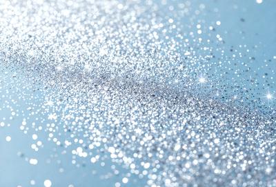 The primary subject of the image is a close-up of a sparkling, glittering surface, possibly a piece of glitter or a shiny surface. The setting is a blue background, which adds to the overall atmosphere of the image. The visual style appears to be a photo, as it captures the details and texture of the glittering surface. The colors and mood of the image are predominantly blue and sparkling, creating a sense of brightness and shine.