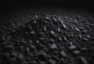 The primary subject of the image is a pile of black rocks. The setting is a dark room, and the visual style appears to be a photo. The dominant colors are black and grey, creating a moody atmosphere. The rocks are scattered and piled on top of each other, giving the impression of a mountain of rocks.