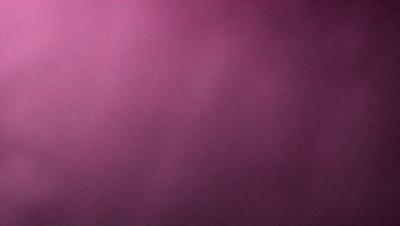 The primary subject of the image is a pink background. The setting is a dark, foggy environment, creating a moody atmosphere. The visual style is a close-up of the pink background, which appears to be a pattern or texture. The colors and mood of the image are predominantly pink, with a hint of darkness from the fog.