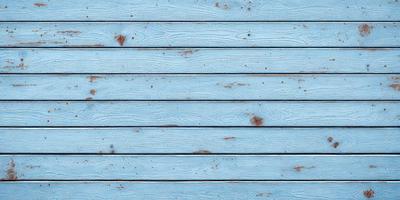 The primary subject of the image is a wooden surface with a blue background. The setting appears to be a wooden deck or a similar outdoor space. The visual style of the image is a close-up of the wooden surface, which gives it a textured and natural appearance. The dominant colors in the image are blue and brown, creating a calm and relaxing atmosphere.
