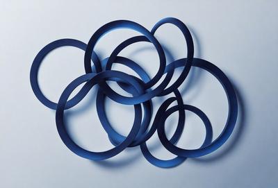 The primary subject of the image is a collection of blue rings or circles, which are arranged in a visually appealing manner. The setting is a white background, which provides a clean and uncluttered environment for the rings to stand out. The visual style of the image is a combination of photo and digital art, as the rings are displayed in a way that resembles a pattern or a collage. The dominant colors in the image are blue, which gives the scene a calm and soothing atmosphere.