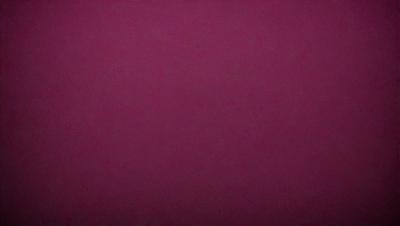 The primary subject of the image is a large, dark red surface. The setting appears to be a dark room, with the red surface being the main focus. The visual style of the image is a close-up of the red surface, which gives it a dramatic and intense appearance. The colors and mood of the image are dominated by the deep red hue, creating a sense of mystery and intensity.