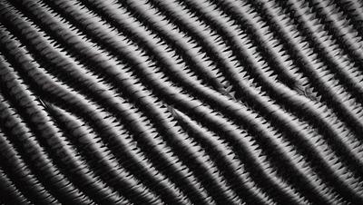 The primary subject of the image is a close-up of a black and white patterned fabric. The setting is a black background, which emphasizes the pattern. The visual style is a combination of a photo and a digital art, illustration, or drawing. The dominant colors are black and white, creating a classic and timeless atmosphere.