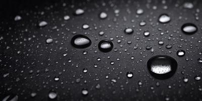 The primary subject of the image is a close-up of a raindrop on a black surface. The setting is a rainy day, and the visual style is a photo. The dominant colors are black and white, with the raindrop being the only color visible. The overall atmosphere is calm and serene, as the raindrop is the main focus of the image.