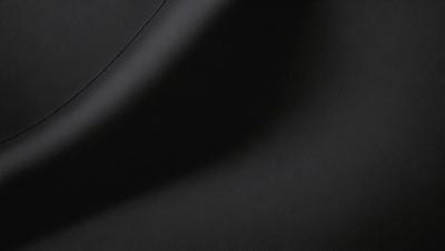 The primary subject of the image is a black leather seat. The setting is a dark room, and the visual style is a close-up of the seat. The colors and mood of the image are predominantly dark, with the black leather seat being the main focus.