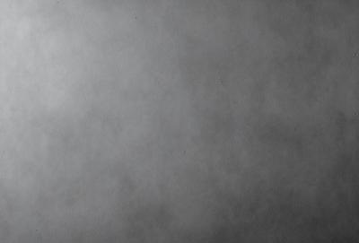 The primary subject of the image is a large, gray, foggy surface. The setting is a cloudy sky, and the visual style is a black and white photo. The colors and mood of the image are predominantly dark and moody, with the gray fog creating a sense of mystery and depth.