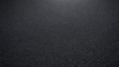 The primary subject of the image is a black asphalt surface. The setting is a dark, empty parking lot. The visual style is a photo, and the colors and mood are dark and moody.