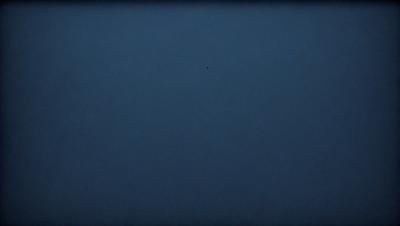The primary subject of the image is a blue sky with a single dot in the middle of it. The sky appears to be cloudless, and the dot is the only visible object in the scene. The visual style of the image is a photo, and the colors and mood are predominantly blue, creating a calm and serene atmosphere.