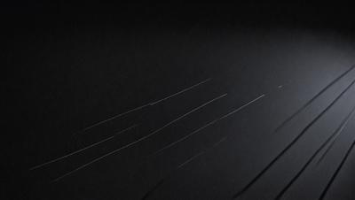 The primary subject of the image is a black background with a white streak or line. The setting is a dark room, and the visual style appears to be a drawing or illustration. The colors are predominantly black and white, creating a stark and dramatic atmosphere.