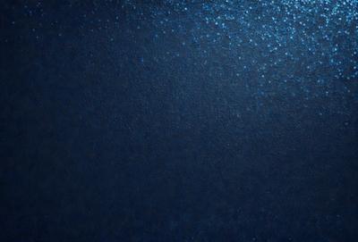 The primary subject of the image is a blue background with a few white specks. The setting appears to be a dark, possibly underwater, environment. The visual style is a close-up of the blue background, which gives the image a moody and atmospheric feel. The colors and mood of the image are predominantly dark and mysterious, with the blue background and white specks adding a touch of contrast and interest.