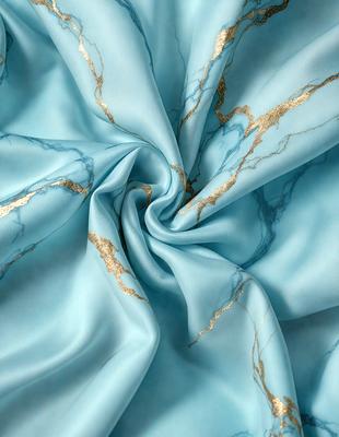 The primary subject of the image is a blue fabric with gold accents. The setting is a blue background, and the visual style appears to be a photo. The colors and mood of the image are predominantly blue and gold, creating a sense of elegance and sophistication.