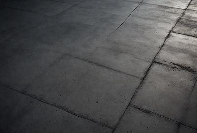 The primary subject of the image is a large, grey, concrete floor. The setting is a room with a concrete surface, and the visual style is a photo. The colors and mood of the image are predominantly grey and neutral, giving it a somewhat dull and uninviting atmosphere.