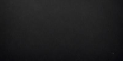 The primary subject of the image is a black leather surface. The setting is a dark room, and the visual style is a close-up of the leather surface. The colors and mood of the image are predominantly dark and moody, with the black leather serving as the focal point.