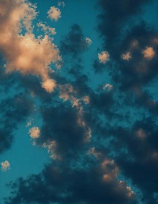The primary subject of the image is a cloudy sky with a blue background. The setting is a cloudy day, and the visual style is a photo. The sky is filled with clouds, and the dominant colors are blue and gray. The overall atmosphere is calm and serene.