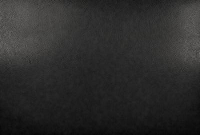 The primary subject of the image is a black leather seat. The setting is a black background, which creates a contrast with the leather seat. The visual style is a close-up of the leather seat, showcasing its texture and details. The colors and mood of the image are predominantly dark, with the black leather seat being the main focal point.