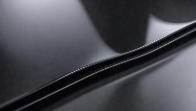 The primary subject of the image is a black metal object, possibly a metal pipe or a metal bar, which is placed on a dark surface. The setting appears to be a dark room or a dark surface, which creates a moody atmosphere. The visual style of the image is a close-up of the metal object, emphasizing its shape and texture. The colors in the image are predominantly black, which adds to the overall mood of the scene.