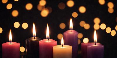 The primary subject of the image is a group of lit candles, with a total of five candles visible. The candles are placed on a table, and they are surrounded by a pattern of dots, creating a visually appealing and festive atmosphere. The setting appears to be a dark room, with the candles providing a warm and inviting glow. The visual style of the image is a close-up of the lit candles, emphasizing their beauty and the intricate pattern of dots surrounding them. The colors