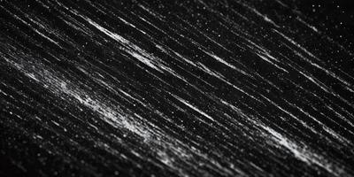 The primary subject of the image is a black background with white streaks or lines. The setting appears to be a dark room, and the visual style is a black and white photo. The dominant colors are black and white, creating a moody and dramatic atmosphere.
