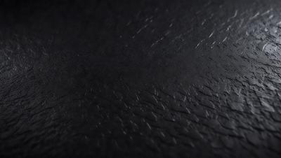 The primary subject of the image is a close-up of a black leather surface. The setting is a dark room, and the visual style is a photo. The dominant colors are black and grey, creating a moody atmosphere.