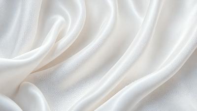 The primary subject of the image is a white fabric, possibly a sheet or a curtain, with a pattern of white dots. The setting is a white background, which creates a clean and minimalist appearance. The visual style is a close-up of the fabric, showcasing its texture and pattern. The colors and mood of the image are predominantly white, giving it a calm and serene atmosphere.