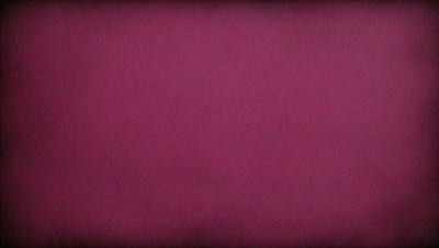 The primary subject of the image is a close-up of a red background. The setting is a dark room, and the visual style appears to be a photo. The dominant colors are red and purple, creating a moody atmosphere.