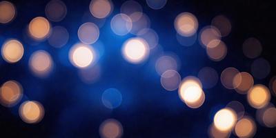 The primary subject of the image is a blue background with a pattern of white lights. The setting appears to be a dark room, and the visual style is a close-up of the blue background with the white lights. The colors and mood of the image are predominantly dark and moody, with the white lights providing a contrasting and somewhat illuminating effect.