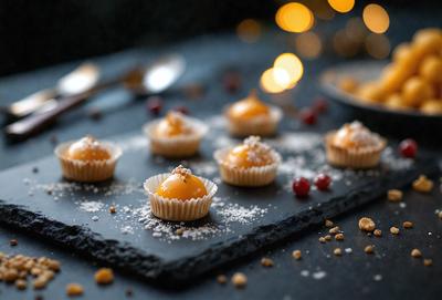 The primary subject of the image is a plate of food, which includes a variety of small pastries and desserts. The plate is placed on a dining table, and the food is arranged in a visually appealing manner. The setting appears to be a cozy and inviting dining space. The visual style of the image is a close-up of the plate, showcasing the details of the pastries and desserts. The colors and mood of the image are warm and inviting, with the pastries