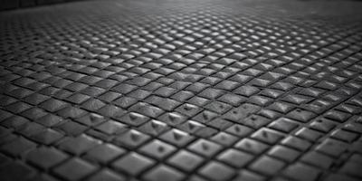 The primary subject of the image is a close-up of a black leather surface with a pattern of small holes. The setting is a black background, and the visual style appears to be a photo. The dominant colors are black and the overall atmosphere is dark and moody.