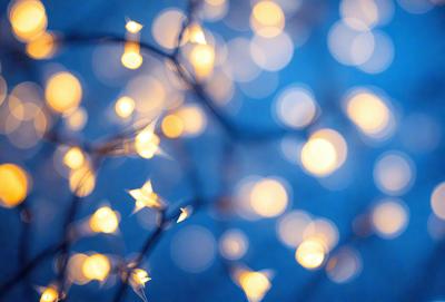 The primary subject of the image is a cluster of bright lights, which are shining in the dark. The setting is a blue background, creating a contrasting and visually appealing scene. The visual style is a combination of a photo and digital art, as the lights are depicted in a realistic manner while the background is digitally created. The colors and mood of the image are predominantly blue, with the bright lights adding a sense of warmth and energy to the scene.