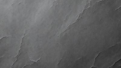 The primary subject of the image is a gray stone wall. The setting is a dark room, and the visual style is a close-up of the stone wall. The colors and mood of the image are predominantly dark and moody, with the gray stone wall being the main focus.