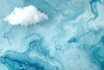 The primary subject of the image is a cloudy sky with a large cloud in the middle. The setting is a blue ocean, creating a serene and calming atmosphere. The visual style is a combination of photo and digital art, as the cloudy sky and ocean are depicted in a realistic manner, while the overall composition and color palette give it a digital art feel. The dominant colors are blue and white, with the cloudy sky and ocean providing a sense of tranquility and beauty.