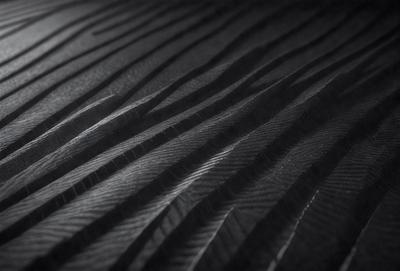 The primary subject of the image is a close-up of a black and white patterned surface. The setting appears to be a dark room, with the patterned surface being the main focus of the image. The visual style is a combination of a photo and a drawing, creating a unique and intriguing appearance. The colors and mood of the image are predominantly dark and moody, with the black and white pattern adding a sense of depth and complexity to the scene.