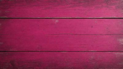 The primary subject of the image is a wooden surface with a pink color. The setting is a room with a wooden floor, and the visual style is a close-up of the wooden surface. The colors and mood of the image are predominantly pink, creating a warm and inviting atmosphere.
