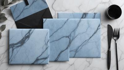 The primary subject of the image is a set of three blue envelopes, each with a different design. The envelopes are placed on a marble surface, which serves as the setting and background of the image. The visual style of the image is a photo, capturing the details and colors of the envelopes. The colors and mood of the image are predominantly blue, giving it a calm and sophisticated atmosphere.