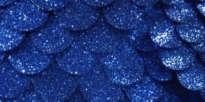 The primary subject of the image is a blue glittery surface, which appears to be a blue fabric or a blue background with glittery elements. The setting is a close-up view of the blue fabric or background, showcasing the glittery texture. The visual style is a combination of a photo and digital art, as the glittery elements are digitally created and added to the blue fabric or background. The colors and mood of the image are predominantly blue, with a touch of glittery sparkle