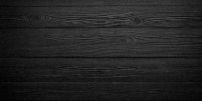 The primary subject of the image is a wooden wall. The setting is a dark room, and the visual style is a black and white photo. The colors and mood of the image are predominantly dark, creating a moody atmosphere.