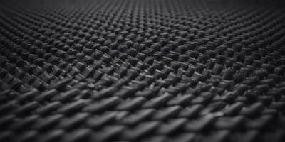 The primary subject of the image is a black mesh material, which appears to be a woven fabric. The setting is a black background, which provides a stark contrast to the mesh material. The visual style of the image is a close-up of the mesh material, showcasing its texture and pattern. The colors in the image are predominantly black, giving the image a dark and moody atmosphere.