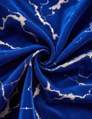 The primary subject of the image is a blue fabric with a pattern of gold stars. The setting is a close-up of the fabric, showcasing its intricate design. The visual style is a detailed, up-close view of the fabric, which gives it a textured and artistic appearance. The colors and mood of the image are predominantly blue and gold, creating a sense of elegance and sophistication.