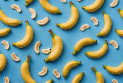 The primary subject of the image is a large number of bananas, which are arranged in a pattern on a blue surface. The bananas are of various sizes and are spread across the entire image. The visual style of the image is a close-up of the bananas, showcasing their details and textures. The colors and mood of the image are predominantly blue and yellow, creating a vibrant and lively atmosphere.