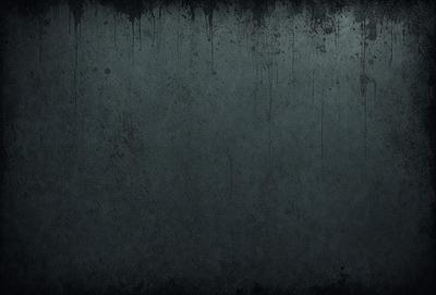 The primary subject of the image is a large, dark grey wall with a few splatters of paint on it. The setting is a room with a grey background, and the visual style appears to be a photo. The colors and mood of the image are dark and moody, with the grey wall and splatters of paint adding to the overall atmosphere.
