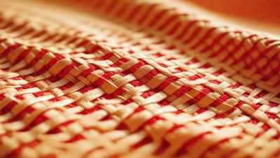 The primary subject of the image is a close-up of a red and yellow woven fabric. The setting is a wooden surface, and the visual style appears to be a photo. The dominant colors in the image are red and yellow, creating a warm and vibrant atmosphere.