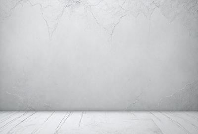The primary subject of the image is a white wall with a gray texture. The setting is a room with a wooden floor. The visual style is a photo, and the dominant colors are white and gray. The overall atmosphere is clean and minimalistic.